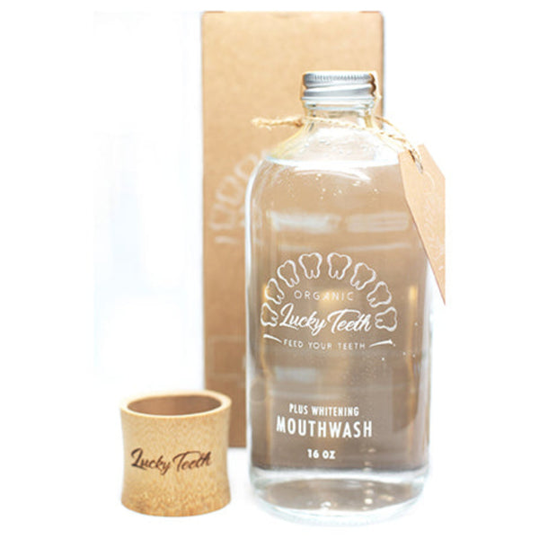 Glass mouthwash bottle and small cup with 'Lucky Teeth' branding on a white background