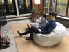 Two children sitting on bean bags in a patio area with a lamp and rug.