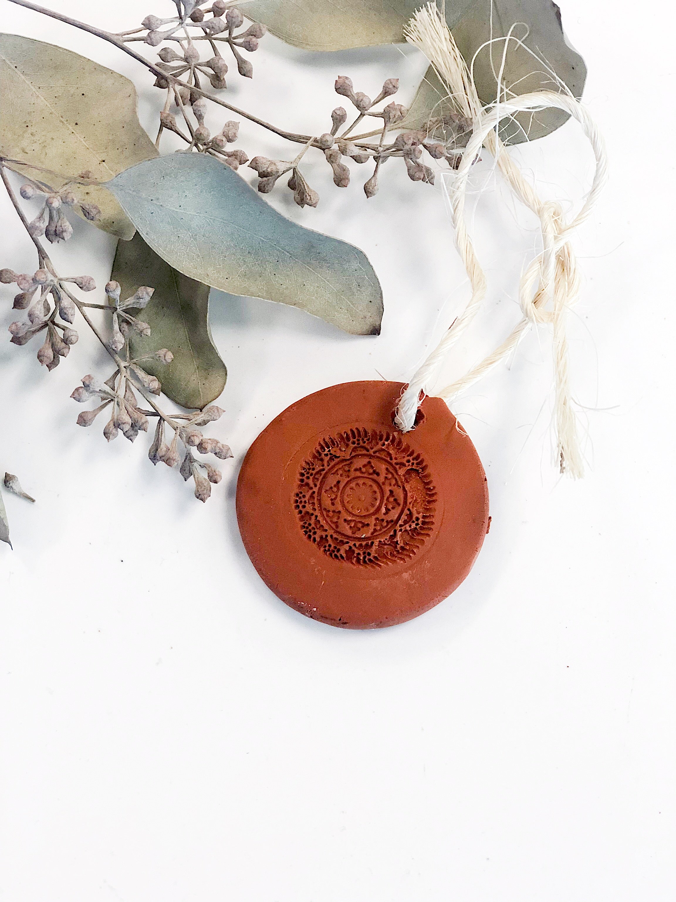 Natural terra cotta clay air freshener disc with organic essential oils, shown close up
