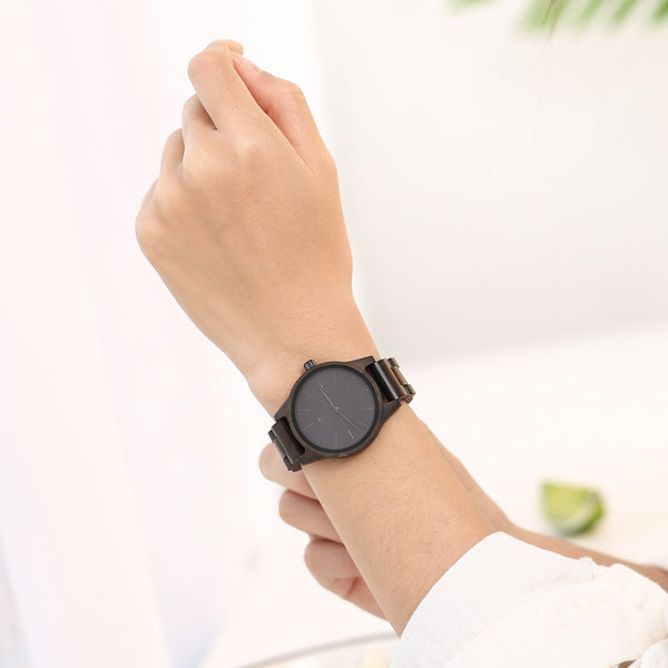 Hand wearing a black wristwatch on a blurred background