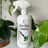 White spray bottle labeled 'Elm Dirt Sword' with green leaves in the background