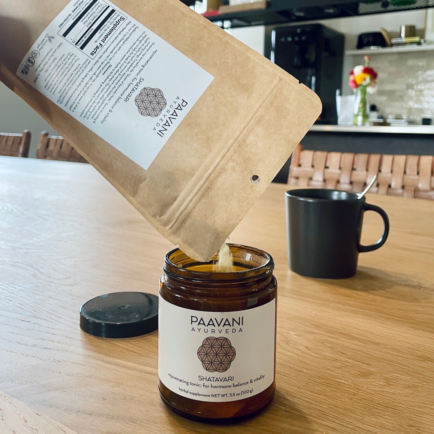 Paavani Ayurveda product being poured from a brown paper bag into a jar on a wooden table.