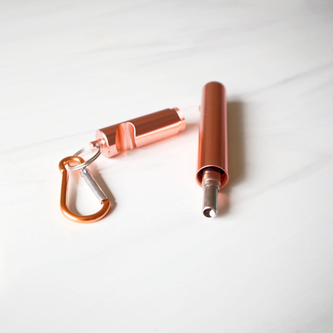 Copper-colored carabiner and cylindrical container on a white background