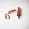 Copper-colored carabiner and cylindrical container on a white background