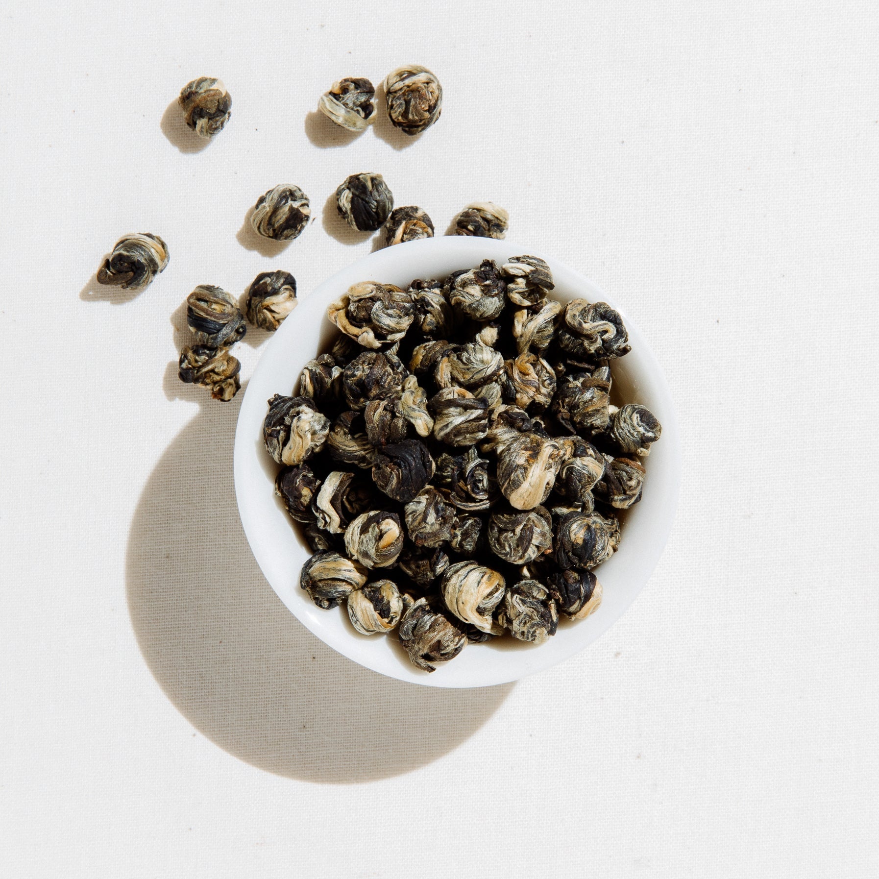 White bowl filled with dried tea leaves on a light background