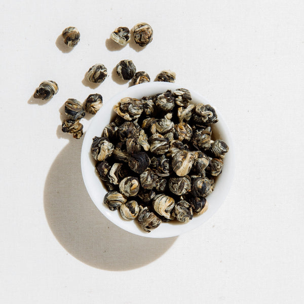 White bowl filled with dried tea leaves on a light background