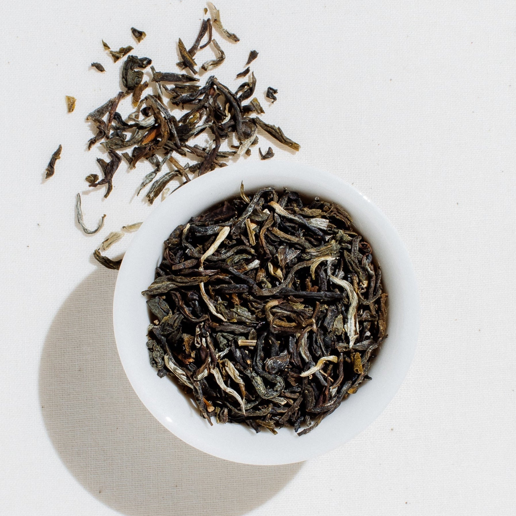 Loose-leaf Jasmine Reserve organic green tea by Art of Tea displayed in a small white bowl on a clean white background, showing the delicate dried tea leaves