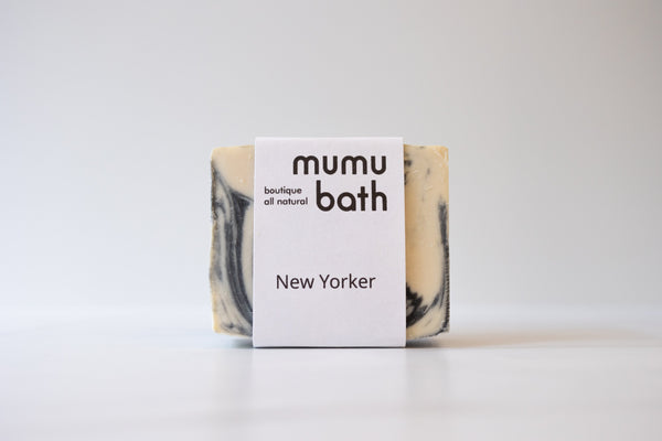 A close-up of the soap bar, showing the black and white color and the Mumu Bath logo.