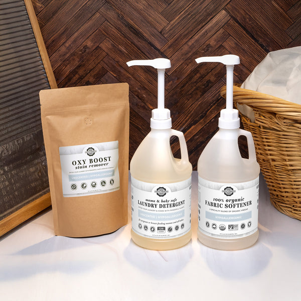 Two bottles of laundry detergent and fabric softener, a bag labeled 'Oxy Boost', and a woven basket on a wooden floor.