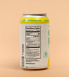 A 12 oz aluminum can of Kombucha with a white label, yellow accents, and a silver top, shown from the back with the Nutrition Facts label visible against a solid peach background.