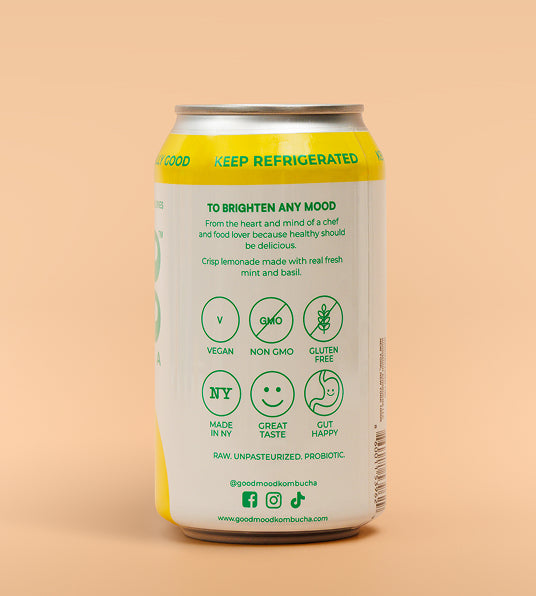 A 12 fl oz can of Good Mood Kombucha on a solid peach background. The can features a white label with green text and icons, and yellow accents at the top and bottom.