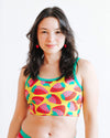 Woman wearing a colorful strawberry-patterned top against a white background