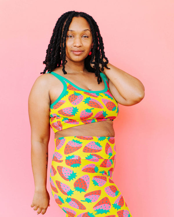 Woman wearing a colorful fruit-patterned outfit on a pink background