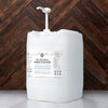 Large white container of spray cleaner with a label on a wooden background