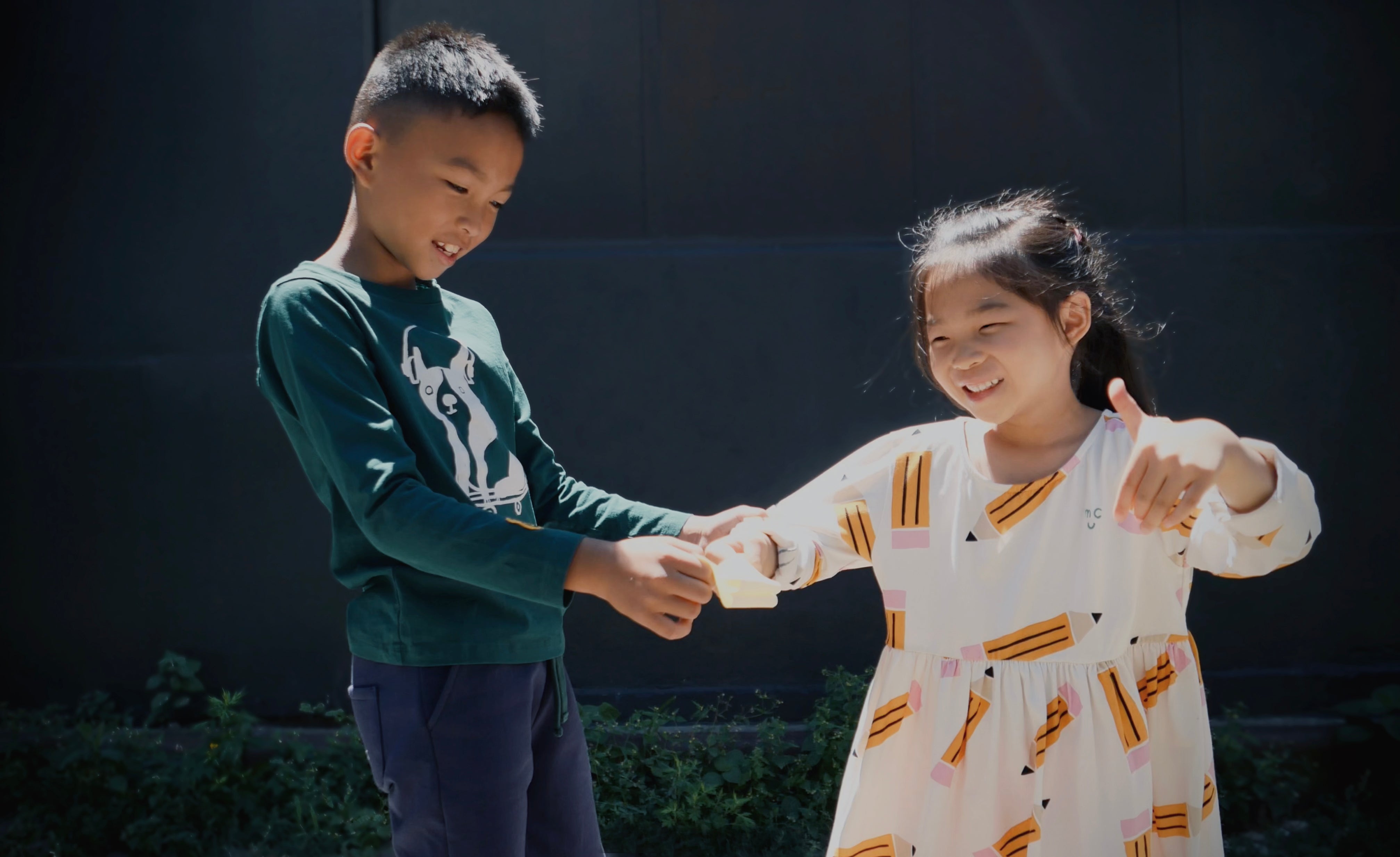 Two children holding hands against a dark background