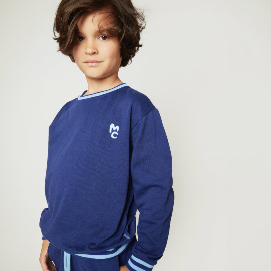 Child wearing the Mon Coeur MC Navy Sweatshirt with striped rib trim at collar and cuffs
