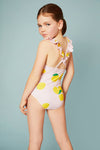 Young girl wearing a pink swimsuit with lemon pattern on a light gray background