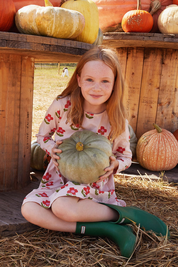 Young girl holding a pumpkin in an outdoor setting with pumpkins around