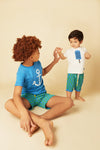 Two children wearing matching outfits with anchors and ice cream graphics on a beige background