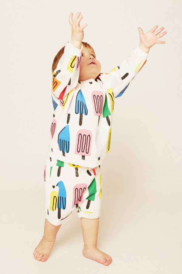 Child wearing a colorful onesie with abstract designs on a plain background