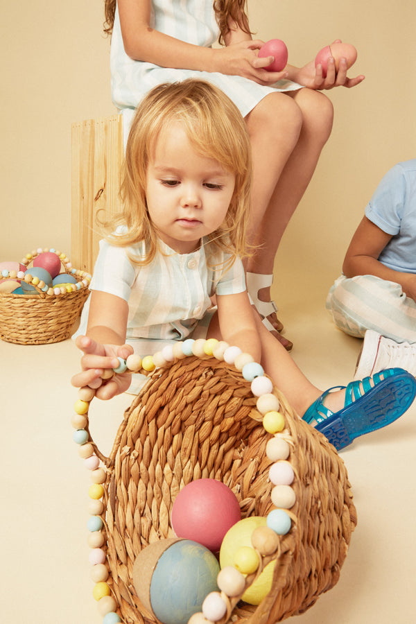 Child playing with a basket of Easter eggs on a beige background