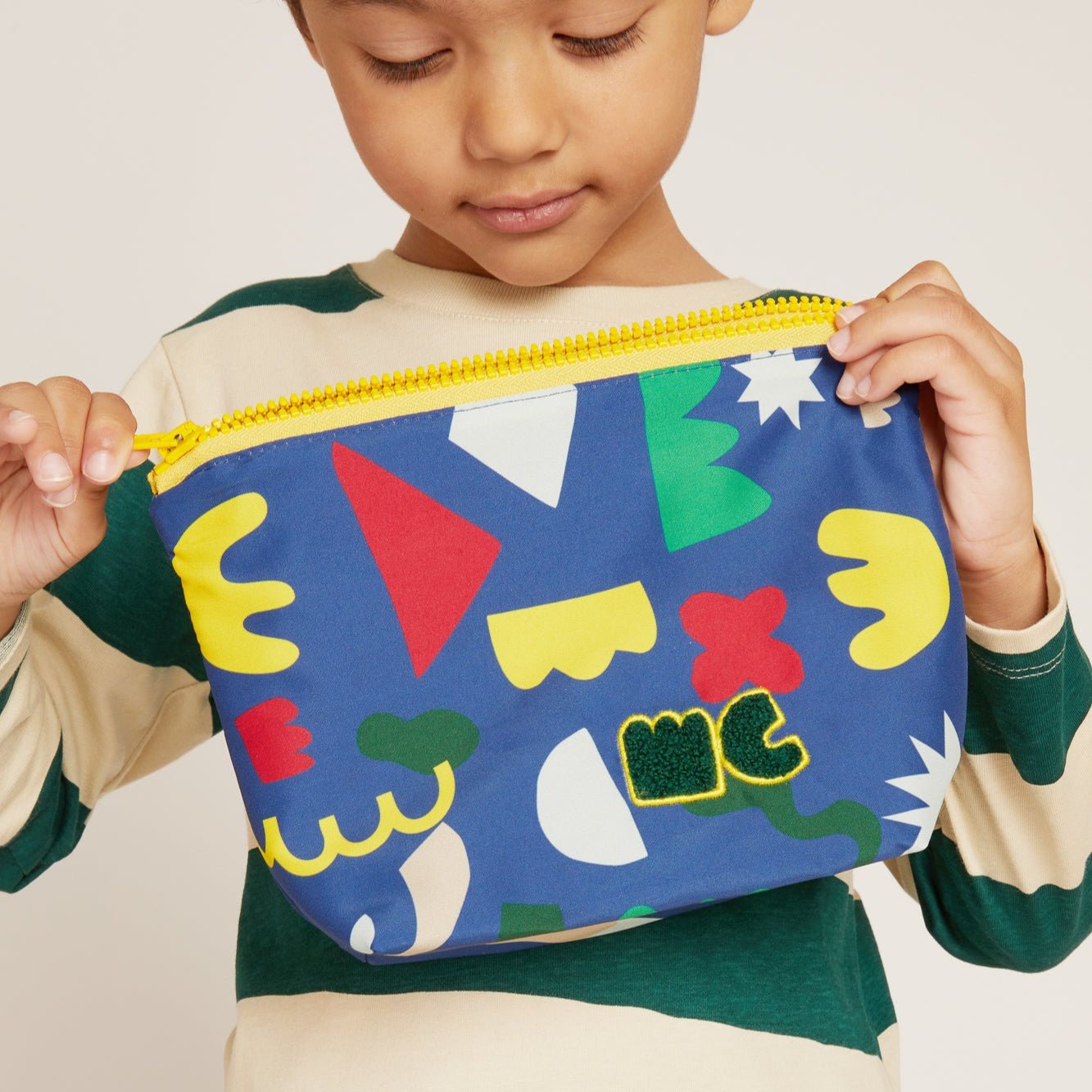 Child holding a colorful geometric-patterned pouch