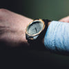 Wooden wristwatch on a person's wrist with a blurred background