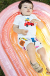Child lying on a colorful inflatable pool float with a car design on a white shirt.