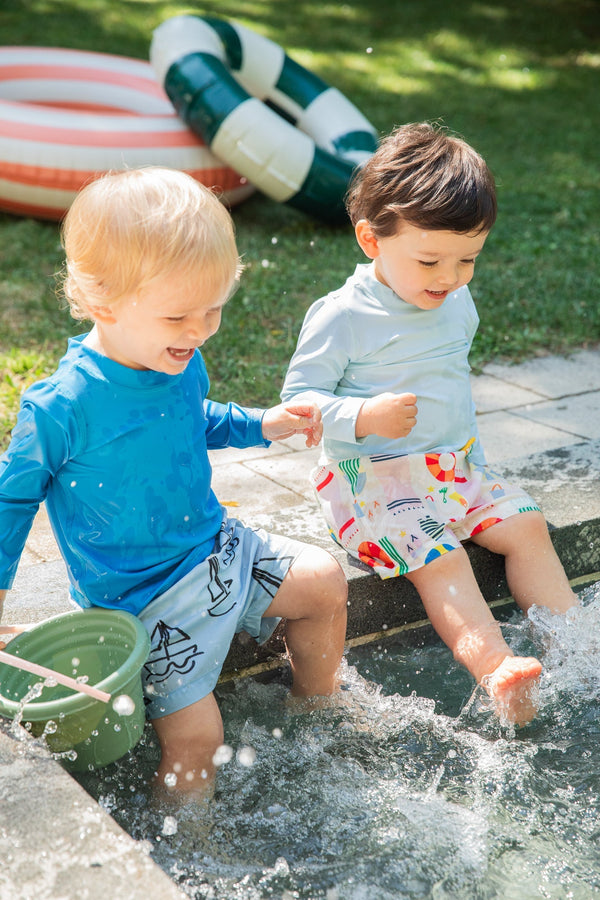 Two children playing in a small pool with inflatable toys in the background.