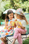 Two young girls sitting on a chair outdoors, enjoying ice cream.