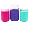 Three mason jar-style cups with colorful silicone sleeves on a white background