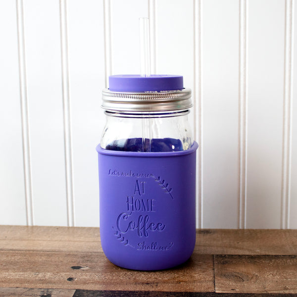 Purple insulated mug with a silver straw lid on a wooden surface.