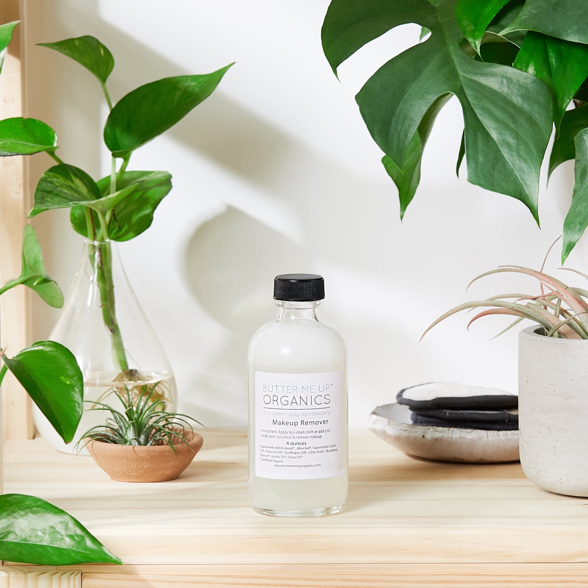 Bottle of organic skincare product on a wooden surface with plants in the background