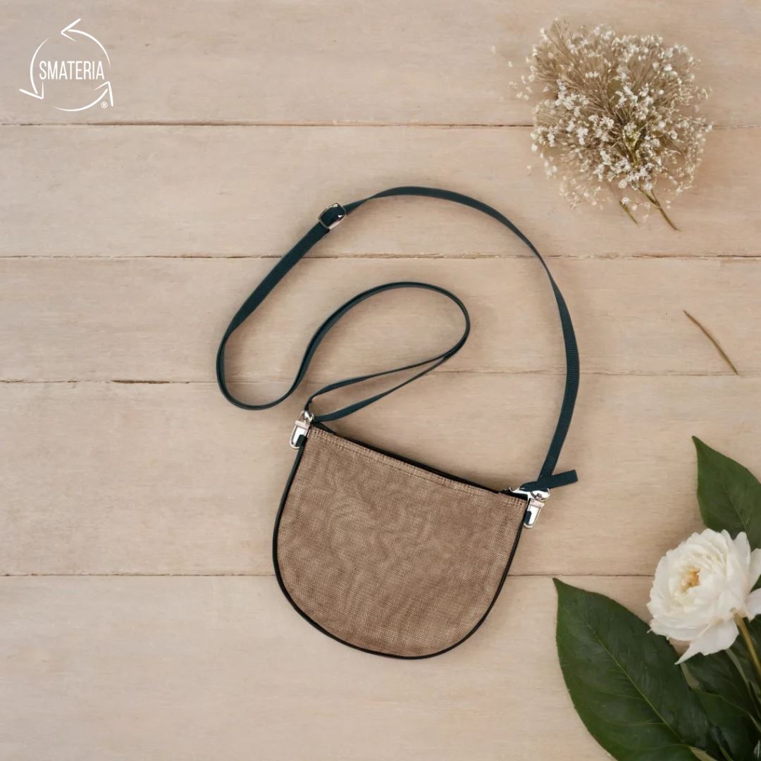 Brown leather crossbody bag on a wooden surface with flowers
