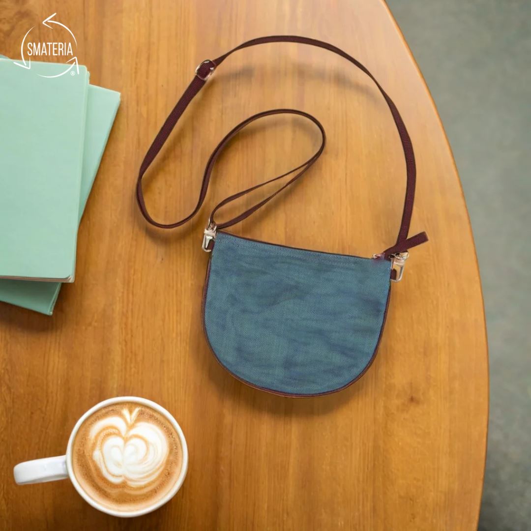 Blue handbag on a wooden table with a cup of coffee and books.