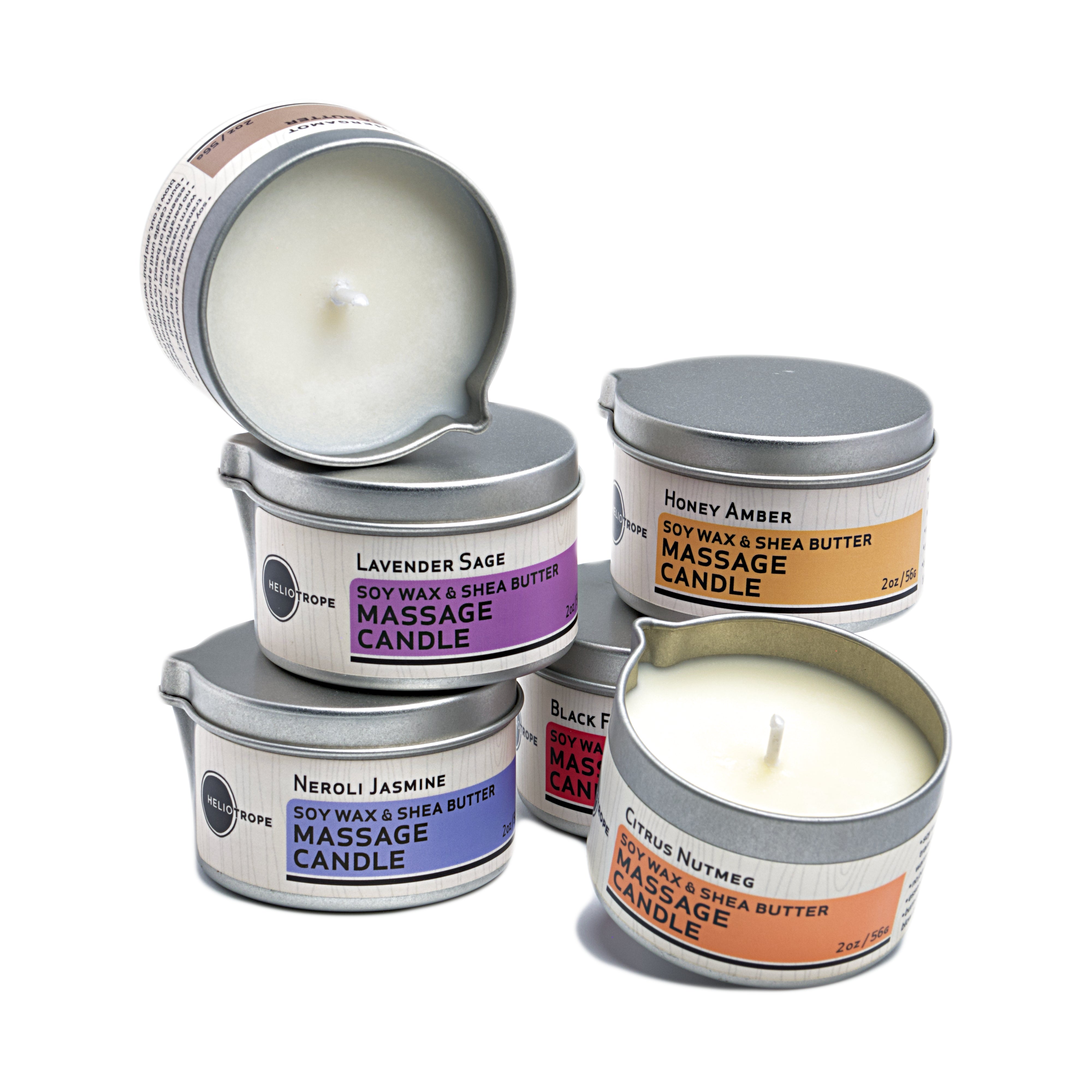 Collection of massage candles in metal tins with visible labels on a white background