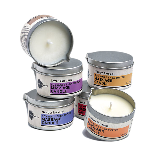 Collection of massage candles in metal tins with visible labels on a white background