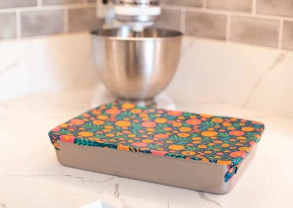 Colorful patterned cutting board on a kitchen counter with a mixer in the background.