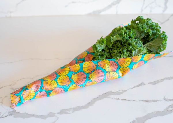 Bunch of kale wrapped in colorful shell-patterned paper on a marble surface