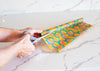 Person cutting colorful paper with scissors on a marble surface