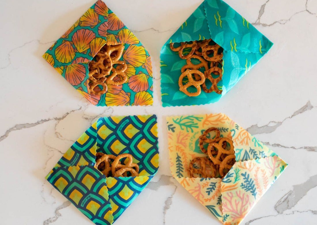 Four colorful fabric bags with pretzels on a marble surface
