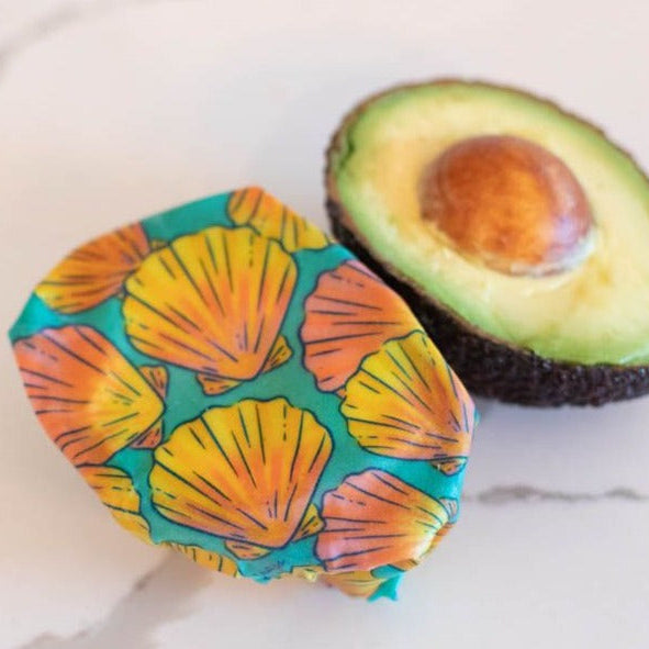 Colorful case with shell pattern next to an avocado on a marble surface