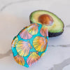 Avocado with a colorful shell-patterned cover on a marble surface