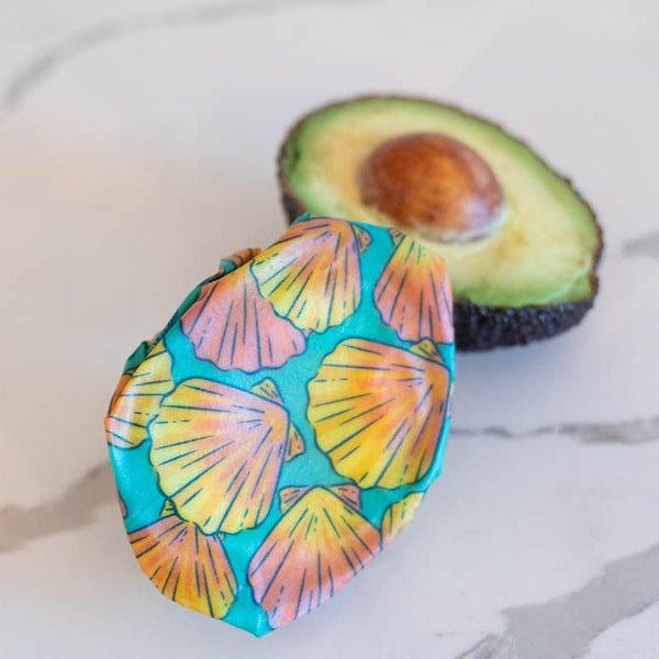 Avocado with a colorful shell-patterned cover on a marble surface