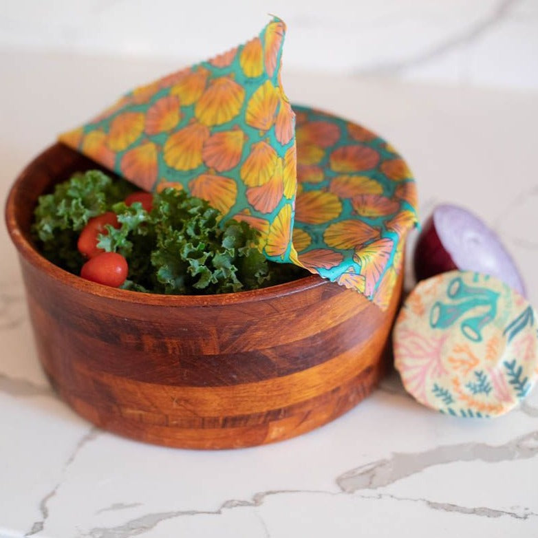 Wooden bowl with salad and a colorful fabric napkin on a marble surface