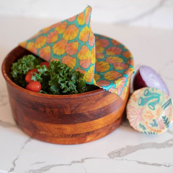 Wooden bowl with salad and a colorful fabric napkin on a marble surface
