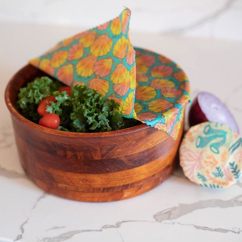 Wooden bowl with salad and a colorful fabric napkin on a marble surface