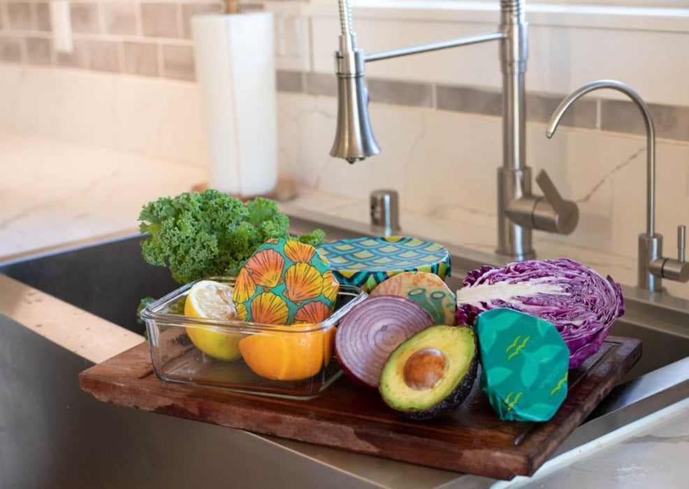 Colorful silicone food covers on vegetables in a kitchen sink