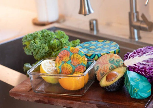 Colorful reusable food wraps on fruits and vegetables in a kitchen setting