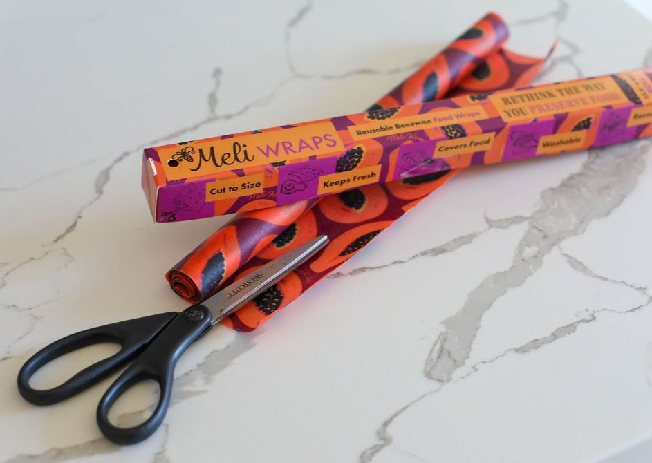Meli Wraps packaging with orange and black design on a marble surface with scissors.